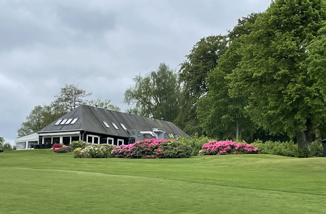 Kokkedal Golfklubs klubhus bag en smuk, faverig rododendronbusk.